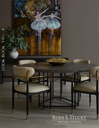 The 2026 Look Book cover. Text: Look Book Vol. 8. Aitne dining table by Baker paired with artwork of Ballerinas on a dark wall.